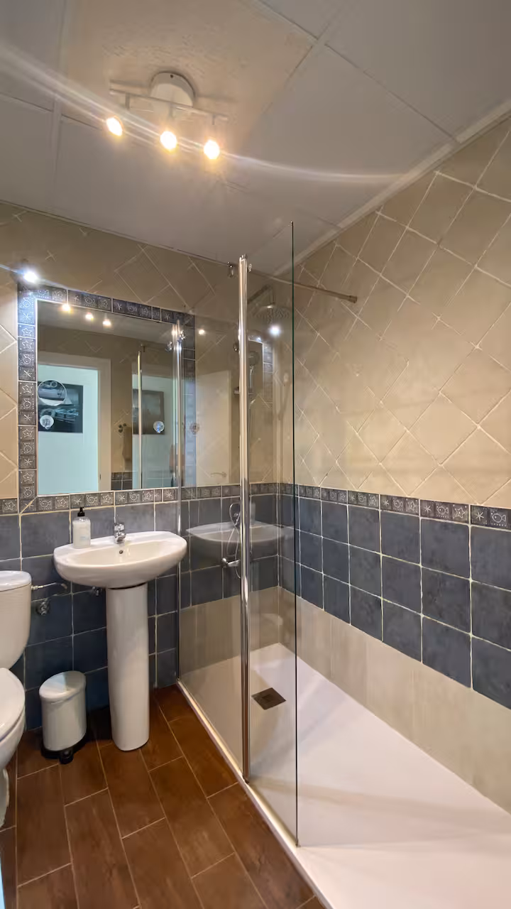 Baño con ducha, lavabo y espejo